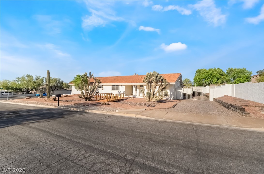 429 Crestway Road Henderson, NV 89015 - Photo 3 of 56 A terracotta-roofed ranch home stands amidst desert landscaping, featuring a gated entrance.