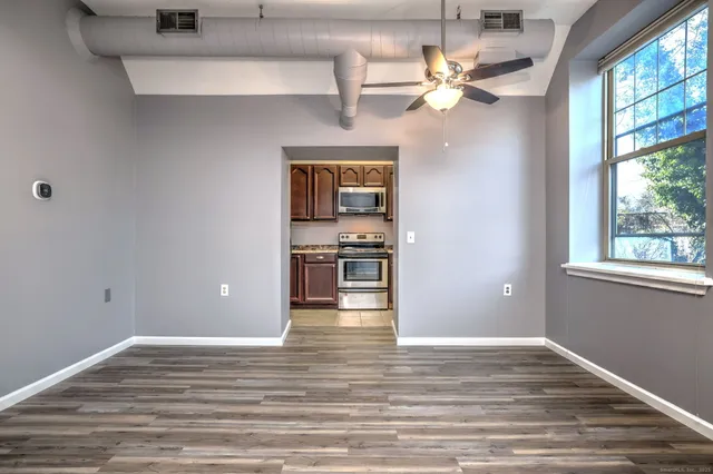 a view of an empty room with window and wooden floor