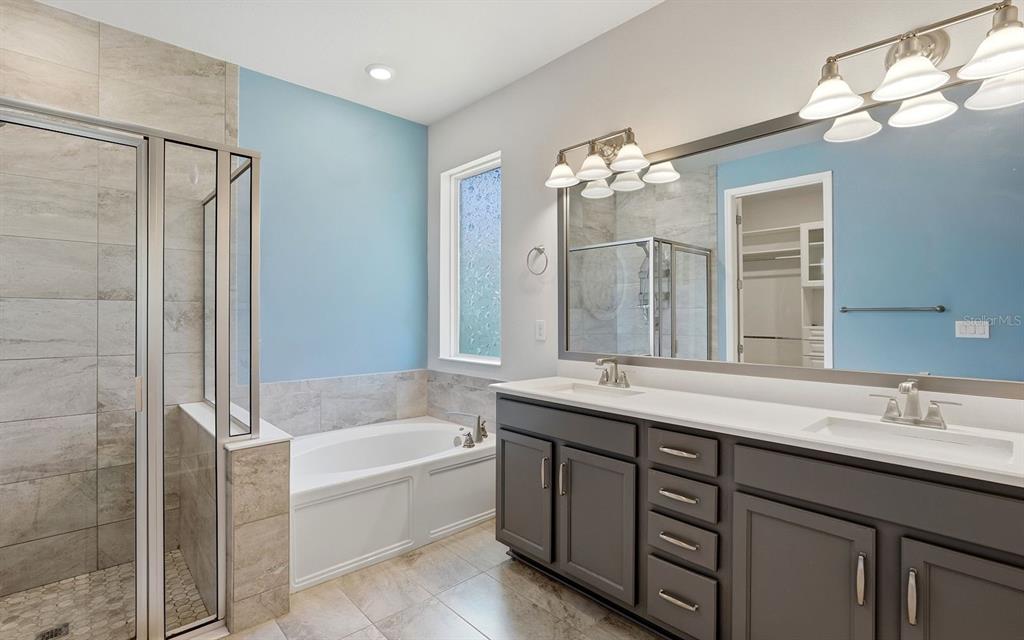 2535 Fireflag Lane Sarasota, FL 34232 - Photo 20 of 27 a bathroom with a tub a double vanity sink and a mirror