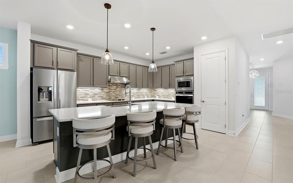 2535 Fireflag Lane Sarasota, FL 34232 - Photo 2 of 27 a kitchen with stainless steel appliances kitchen island granite countertop a table chairs refrigerator and microwave