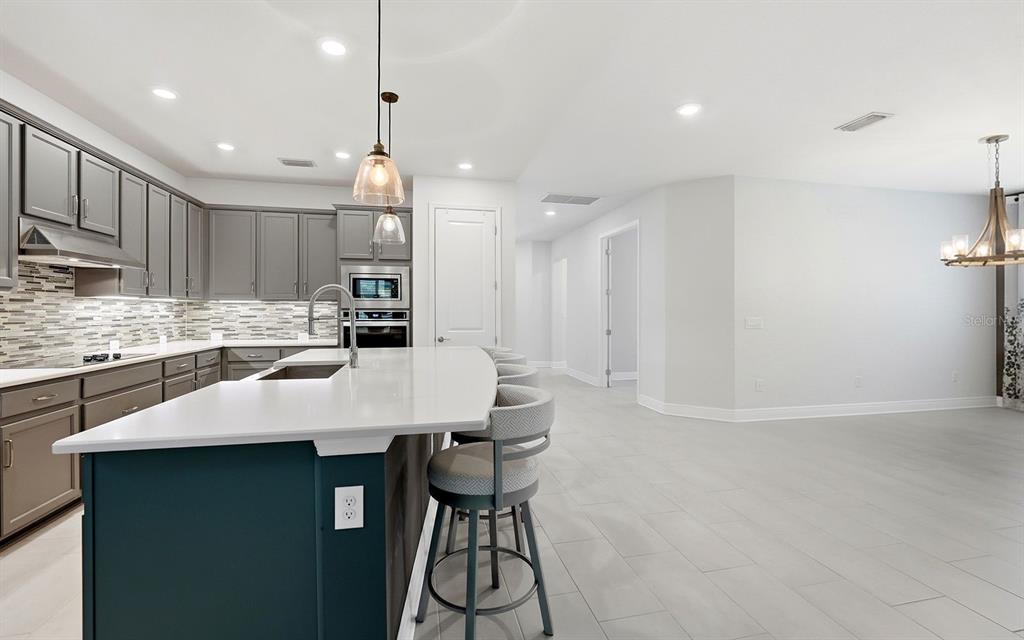 2535 Fireflag Lane Sarasota, FL 34232 - Photo 3 of 27 a kitchen with kitchen island a stove a table and chairs in it