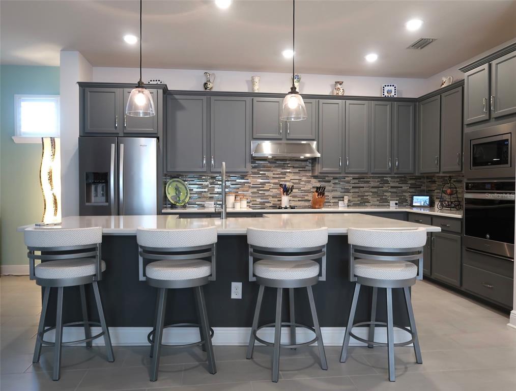 2535 Fireflag Lane Sarasota, FL 34232 - Photo 5 of 17 a kitchen with stainless steel appliances kitchen island granite countertop a table chairs stove and white cabinets