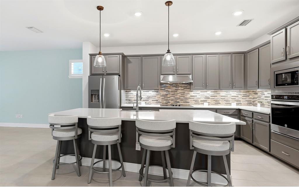 2535 Fireflag Lane Sarasota, FL 34232 - Photo 5 of 27 a kitchen with stainless steel appliances kitchen island granite countertop a table chairs sink and cabinets