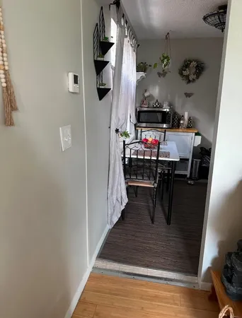 a hallway with a white stove top oven and a dining table with wooden floor