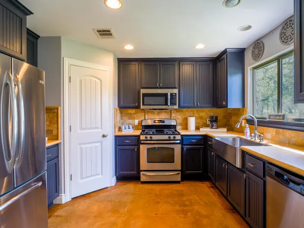 a kitchen with stainless steel appliances granite countertop a stove a refrigerator and a sink