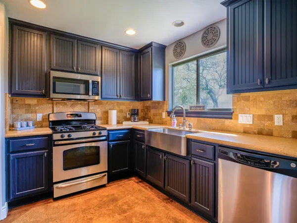 a kitchen with granite countertop cabinets stainless steel appliances and a sink