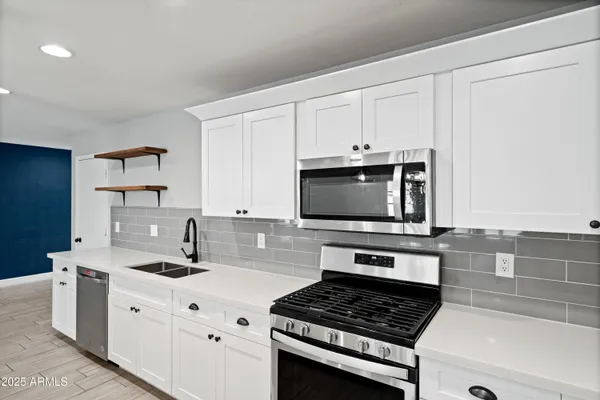 a kitchen with stainless steel appliances granite countertop a sink a stove and a wooden floors