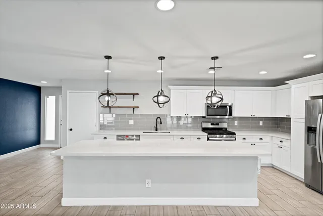 a view of a livingroom with a chandelier fan and kitchen view