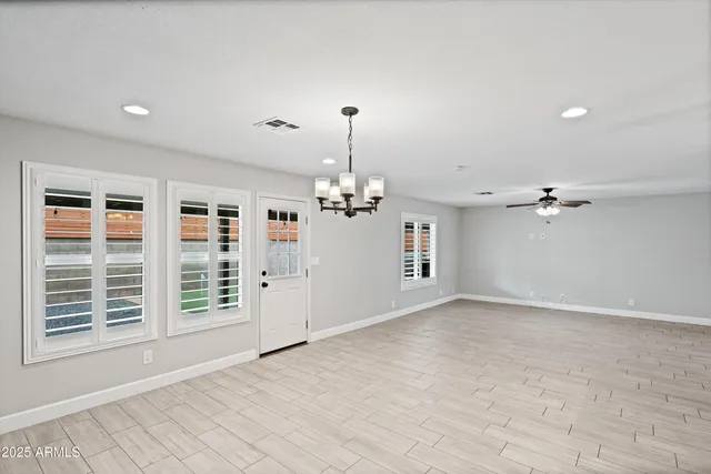 an empty room with windows and ceiling fan