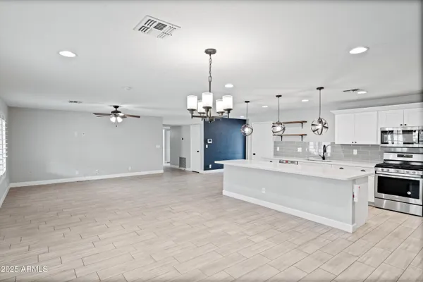 a view of an empty room with kitchen and window