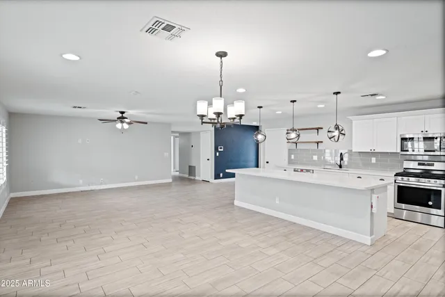 a view of an empty room with kitchen and window