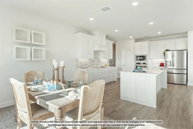 a kitchen with stainless steel appliances kitchen island granite countertop a refrigerator a stove a sink dishwasher and white cabinets with wooden floor