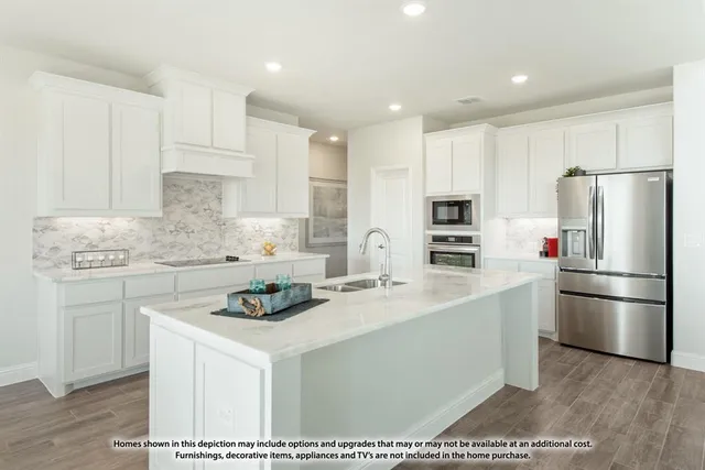 a kitchen with a sink a stove a refrigerator and white cabinets