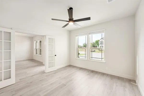 an empty room with wooden floor and windows