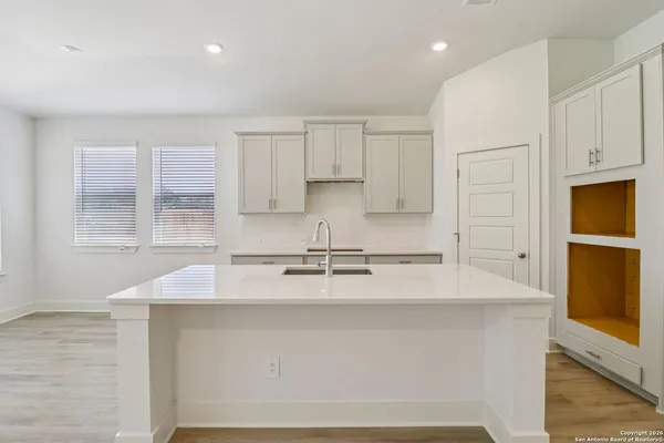 a kitchen with stainless steel appliances granite countertop a sink a stove and white cabinets with wooden floor