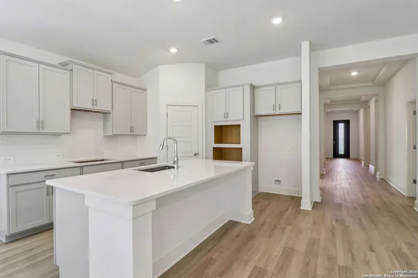 a kitchen with a sink a stove cabinets and wooden floor
