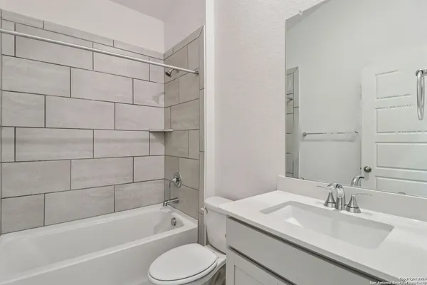 a bathroom with a granite countertop bathtub shower sink vanity and toilet