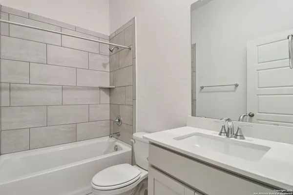 a bathroom with a granite countertop bathtub shower sink vanity mirror and toilet