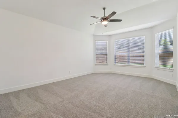 an empty room with windows and fan