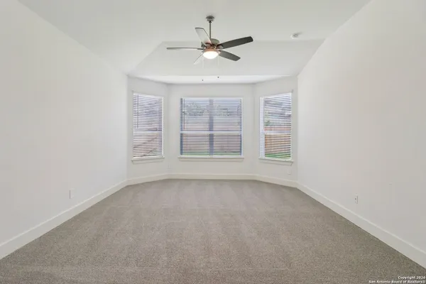 an empty room with windows and ceiling fan
