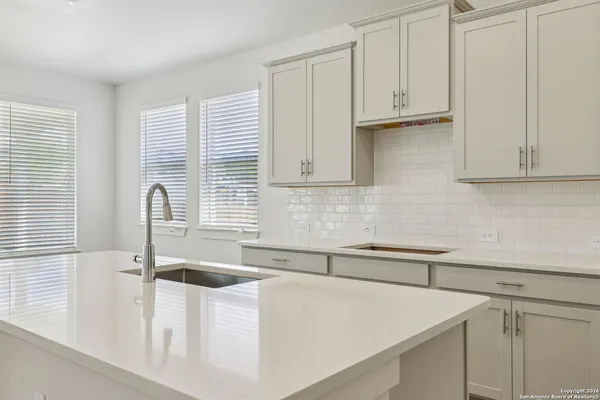 a kitchen with stainless steel appliances granite countertop a sink a stove and white cabinets