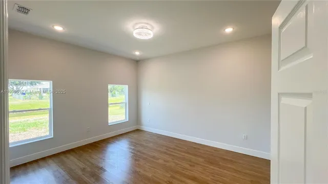 a view of an empty room with wooden floor and closet