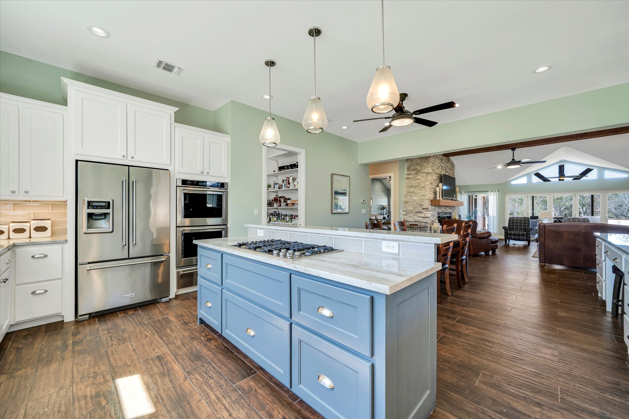 204 West Blanco Bend Drive Wimberley, TX 78676 - Photo 11 of 34 a kitchen with stainless steel appliances kitchen island granite countertop a stove a refrigerator a oven a dining table and chairs with wooden floor