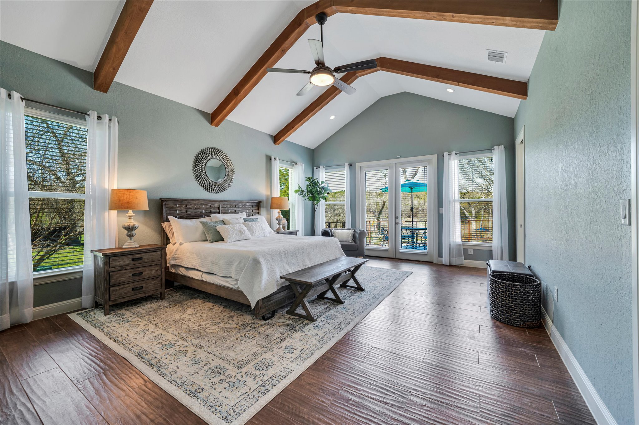 204 West Blanco Bend Drive Wimberley, TX 78676 - Photo 12 of 34 a spacious bedroom with a bed a mirror and a large window with wooden floor