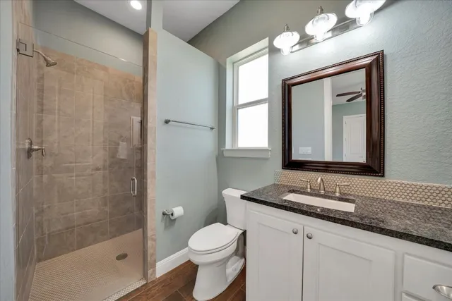 a bathroom with a granite countertop sink a toilet and a mirror