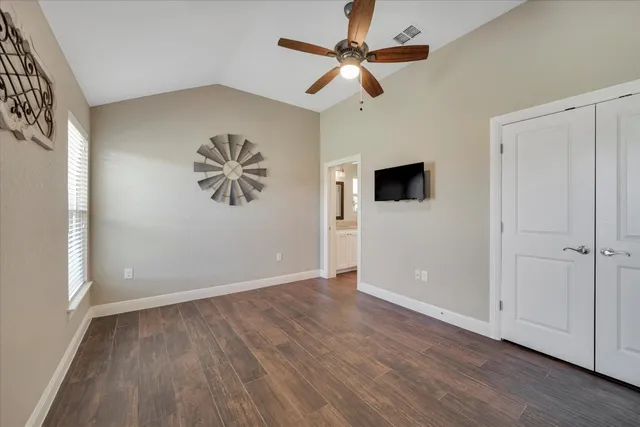 an empty room with wooden floor chandelier fan and windows