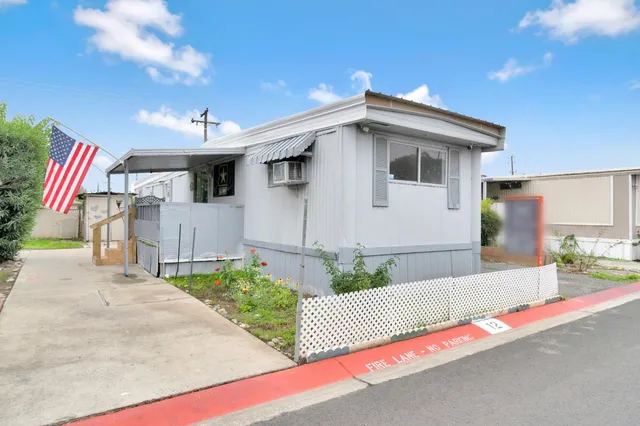 a white house with a sink and yard next to a road