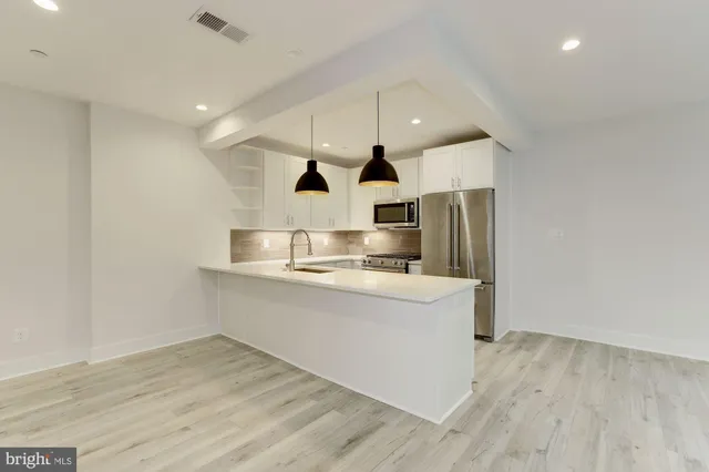 a large kitchen with stainless steel appliances a large counter top and a wooden floors