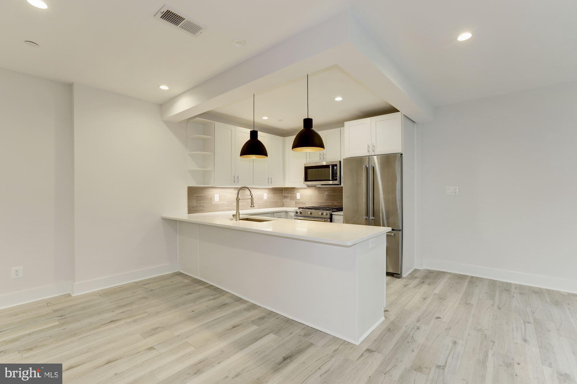 4008 Edmunds Street Northwest, Unit 6 Washington, DC 20007 - Photo 18 of 31 a large kitchen with stainless steel appliances a large counter top and a wooden floors