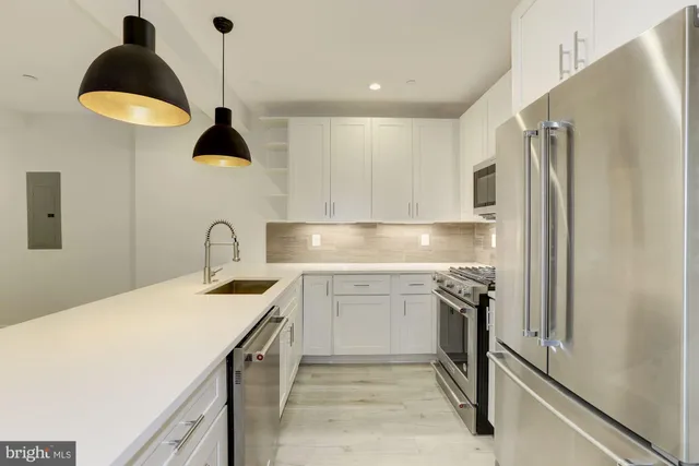 a kitchen with stainless steel appliances granite countertop a sink a stove and a refrigerator