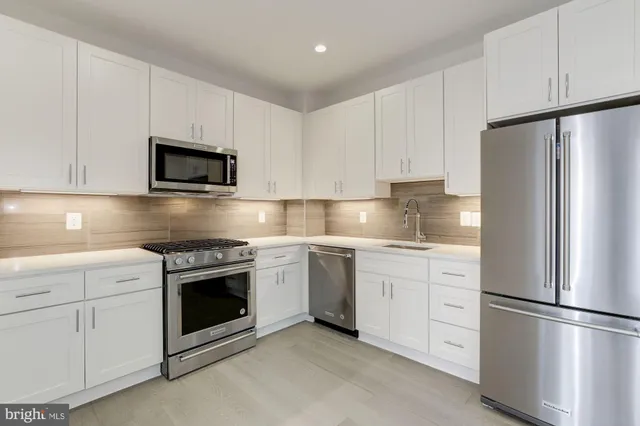 a kitchen with stainless steel appliances granite countertop a refrigerator stove a sink and a microwave