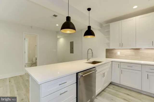 a kitchen with a sink dishwasher and a stove with white cabinets