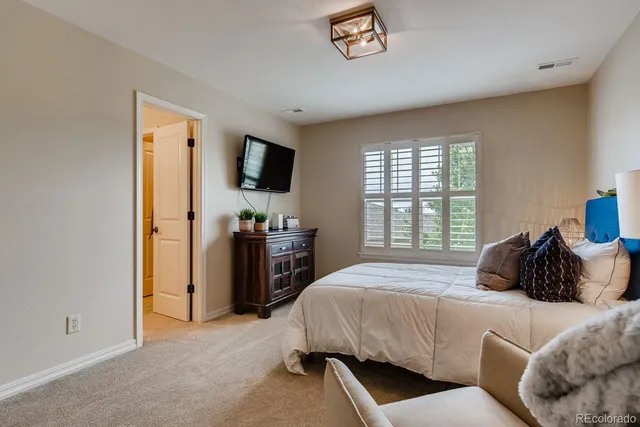 a bedroom with a bed a couch and a flat tv screen on the dresser