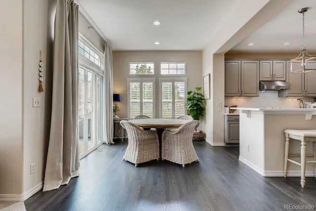 a living room with kitchen island granite countertop wooden floor and a refrigerator