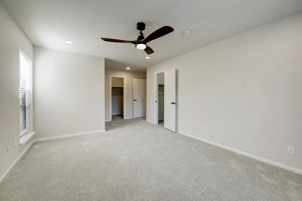 a view of a livingroom with a ceiling fan & windows
