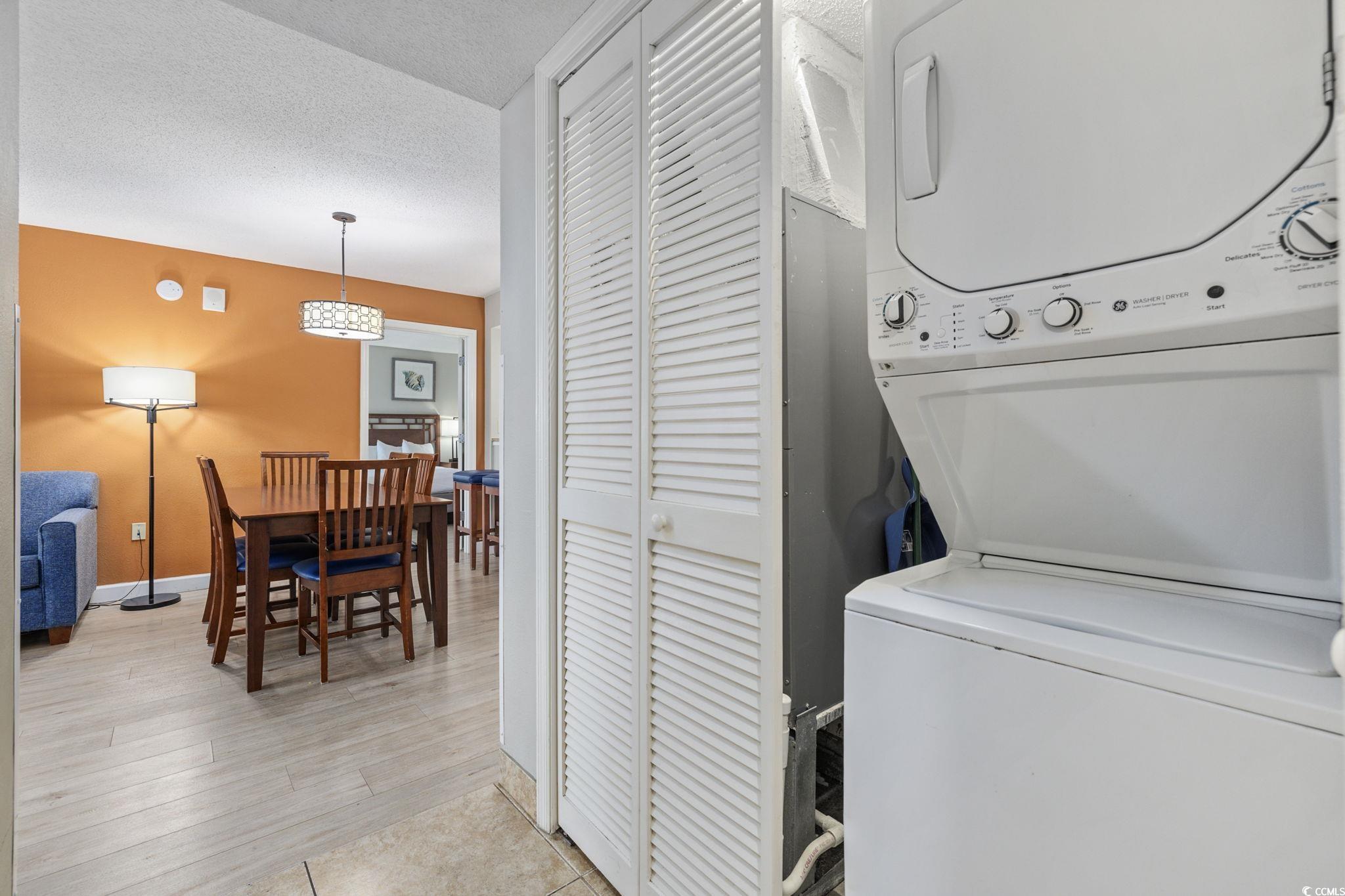 5200 North Ocean Boulevard, Unit 857 Myrtle Beach, SC 29577 - Photo 7 of 40 Laundry room with stacked washing machine and dryer, a textured ceiling, and light tile patterned floors