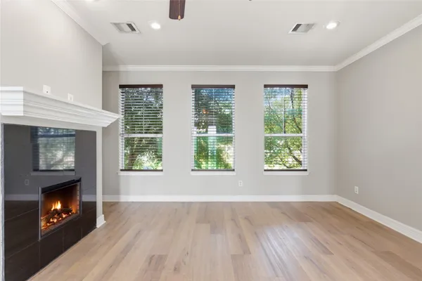 a view of an empty room with chandelier and wooden floor