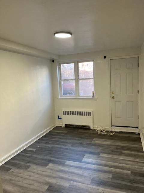 Unfurnished room with radiator heating unit and dark hardwood / wood-style flooring