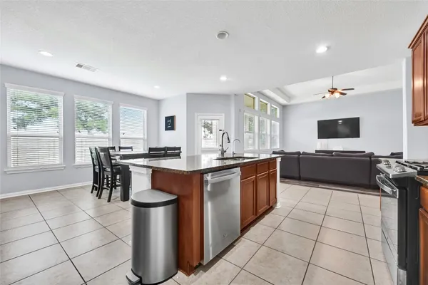 a large kitchen with a large counter top space a sink stainless steel appliances and cabinets