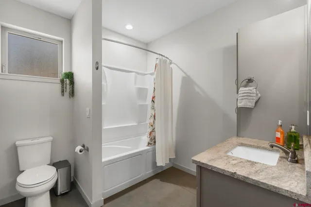 a bathroom with a granite countertop sink a toilet and shower