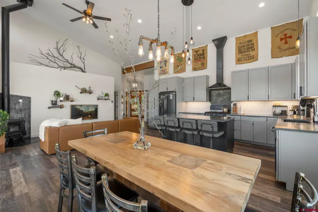 a kitchen with stainless steel appliances kitchen island a table chairs in it and wooden floors