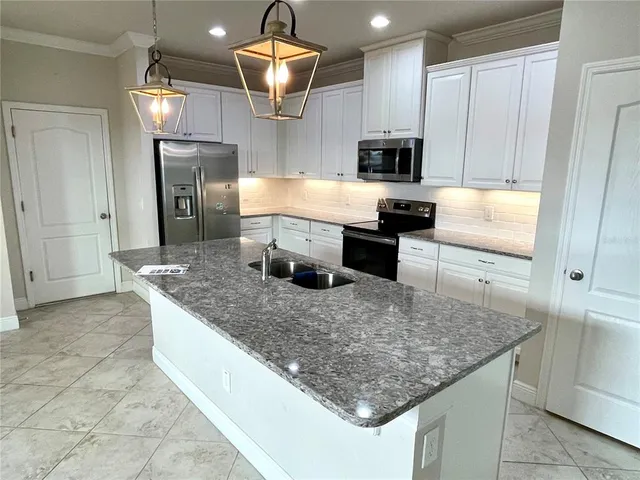 a kitchen with stainless steel appliances granite countertop a stove top oven a sink dishwasher a dining table and chairs