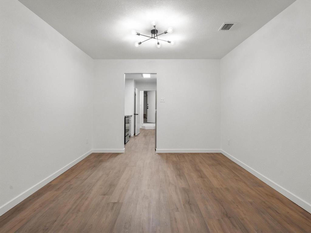 1117 South Rusk Street, Unit 1117 Weatherford, TX 76086 - Photo 11 of 16 Unfurnished room with wood finished floors and a chandelier