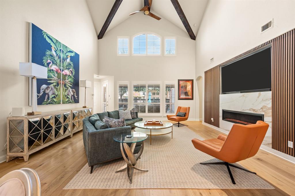 1521 Newton Ranch Road Keller, TX 76248 - Photo 8 of 40 Vaulted ceilings with exposed beams, wood flooring, built-in electric fireplace with stone surround, custom wood accent wall, and arched transom windows