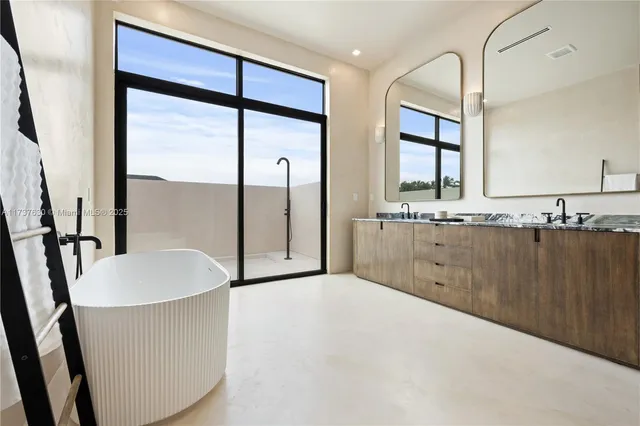 a spacious bathroom with a granite countertop sink a mirror and a bathtub