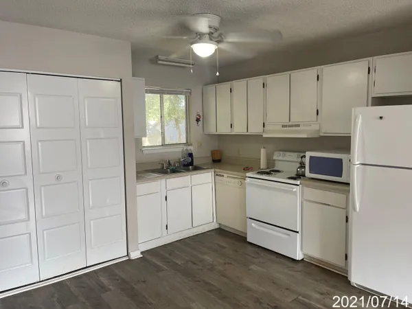 a kitchen with white cabinets and white appliances